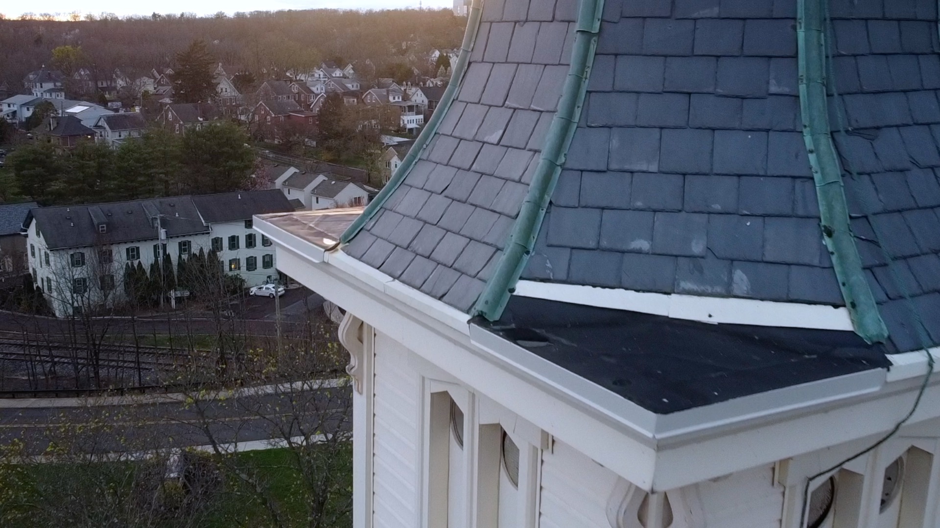 Close-up aerial drone shot of church steeple roofline and clock tower detail